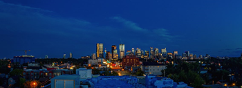 A city skyline at night with buildings lit up.